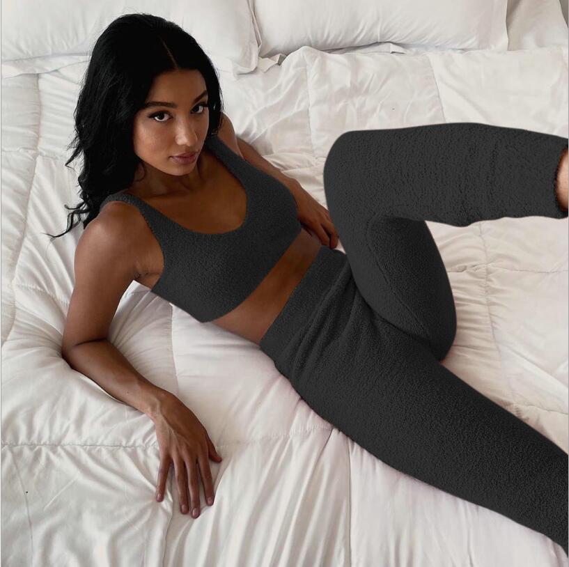 Woman wearing a black 3 piece women's sleepwear set lying on a white bed